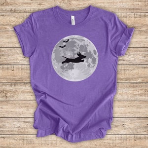 May include: Purple t-shirt with a black silhouette of a dachshund jumping in front of a full moon with bats flying above.