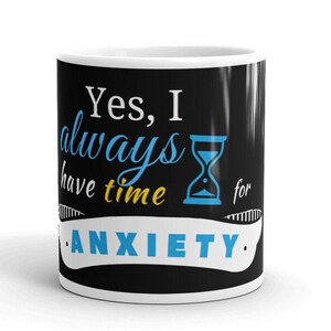 May include: White ceramic mug with a black background and the text "Yes, I always have time for ANXIETY." in white and blue lettering. An hourglass is depicted in blue.