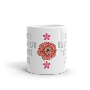May include: White ceramic mug with a large, watercolor-style pink flower and two smaller pink flowers. The mug has black text that reads, "Ready for a laugh? I won't be long. I can tell by that it's getting..."