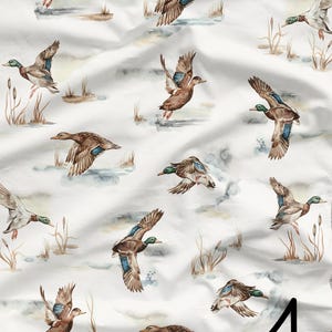 May include: A white background with a repeating pattern of watercolor ducks in flight. The ducks are brown with green heads and wings. The background has a subtle watercolor wash of brown and gray.