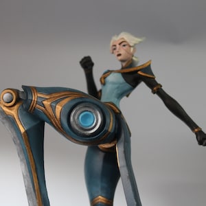 May include: A detailed figurine of a character in a dynamic pose. The figure is predominantly blue with gold accents, and the design suggests a futuristic or fantasy theme. The character has white hair and is in a fighting stance.