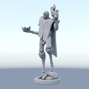 May include: A gray figurine of a humanoid figure with a stylized design. The figure is holding a lotus flower in one hand and a staff in the other. The figure is standing on a round base.