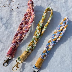 Può includere: Tre portachiavi intrecciati con diverse combinazioni di colori. I portachiavi sono realizzati in corda di cotone e hanno un moschettone in metallo dorato o argentato.