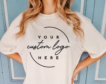 May include: A white oversized t-shirt with a black circle graphic that says "YOUR custom logo HERE".