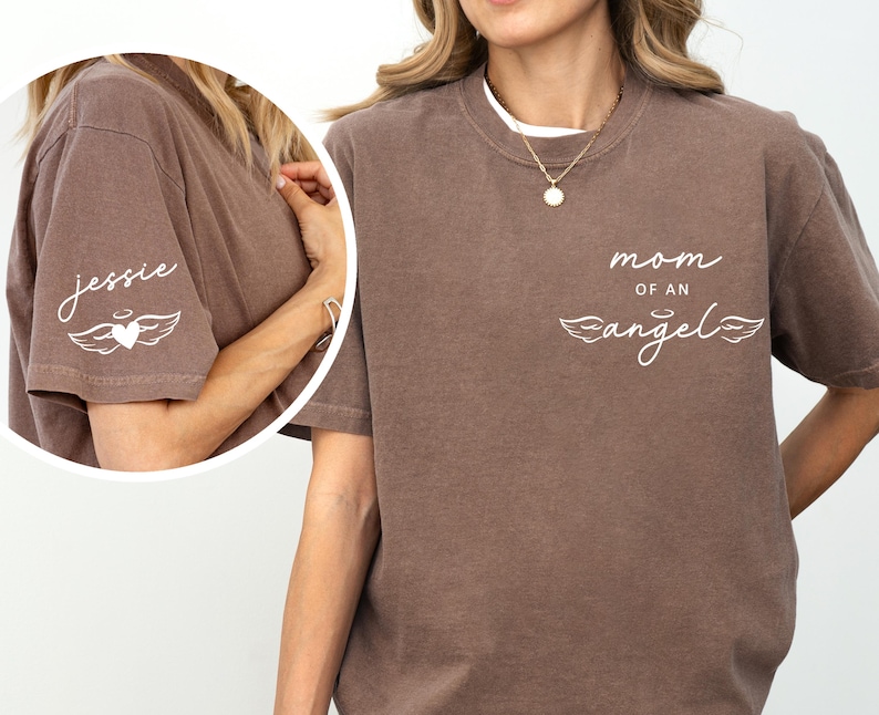 May include: A brown t-shirt with the text "mom of an angel" and angel wings on the front. The left sleeve has the name "jessie" with a heart and wings design. The shirt is a casual style.