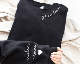 May include: Black sweatshirt with the word "grandma" on the front and the words "custom names" with a white heart on the sleeve.