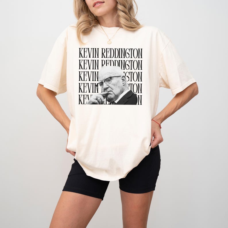 A woman wearing a white t-shirt with a black and white graphic of a man's face and the text "KEVIN REDDINGTON" repeated around the image.