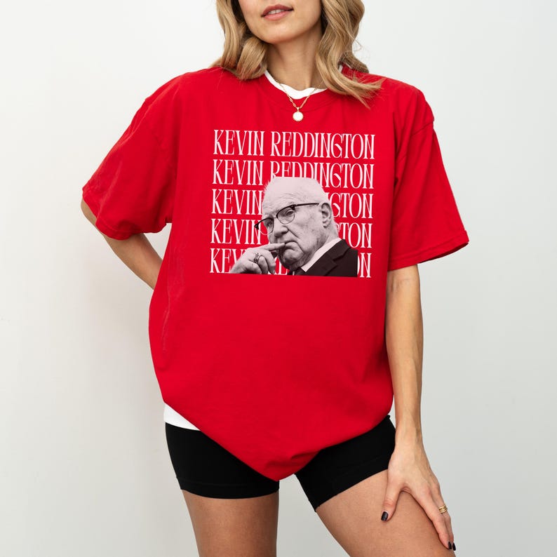 A woman wearing a red t-shirt with a graphic of a man's face and the text "KEVIN REDDINGTON" repeated across the shirt.