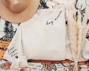 May include: A white sweatshirt with the text "dog mama" on the front and the names "Luna, Cooper, Hera" and a paw print on the left sleeve.