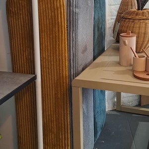 K&ouml;nnte beinhalten: Drei hohe, bogenf&ouml;rmige Wandpaneele, bezogen mit Kordstoff in Senfgelb, Hellgrau und Petrol. Die Paneele sind vertikal an einer Wand angebracht und weisen eine ausgepr&auml;gte gerippte Textur &uuml;ber ihre gesamte Oberfl&auml;che auf.