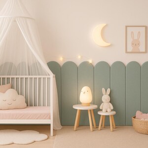 Pode incluir: Um quarto de crian&ccedil;a com um ber&ccedil;o branco, dossel e almofada em forma de nuvem. Uma lua iluminada e luzes de estrelas adornam a parede. Dois pequenos bancos de madeira suportam uma l&acirc;mpada e um coelhinho. Uma cesta de vime cont&eacute;m almofadas.