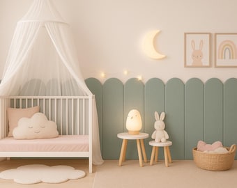 Könnte beinhalten: Ein weißes Holzbettchen mit einem transparenten Betthimmel, einer rosa Matratze und einem wolkenförmigen Kissen. Daneben stehen zwei kleine Holztische mit einer kükenförmigen Lampe und einem Stoffhasen. Eine gewellte, salbeigrüne Wandverkleidung.