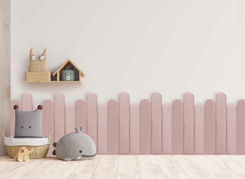 May include: A pink wooden fence with rounded tops, a gray whale plush toy, a gray and white plush toy in a wicker basket, and a wooden shelf with a small house and a cat toy.