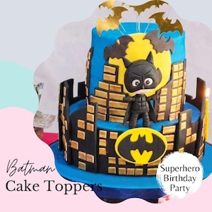 Könnte beinhalten: Eine zweistöckige Batman-Torte mit blauer und schwarzer Glasur, goldenen Akzenten und einer Batman-Figur. Die Torte zeigt ein gelbes Mond- und Stadtlandschaftsdesign mit dem Batman-Logo. Auf der Torte steht "Batman Cake Toppers" und "Superhero Birthday Party."