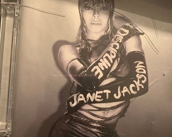 May include: A black and white photo of Janet Jackson on the cover of her album "Discipline".