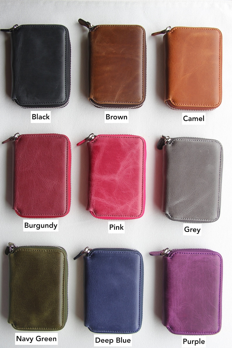 Puede incluir: Nueve carteras de cuero con cremallera de diferentes colores. Las carteras est&aacute;n dispuestas en tres filas de tres. Los colores son negro, marr&oacute;n, camel, burdeos, rosa, gris, verde marino, azul oscuro y morado.