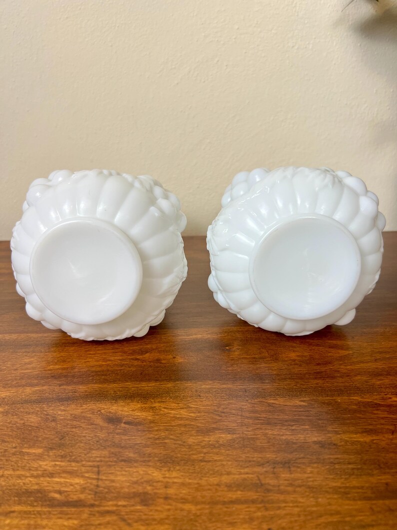 Puede incluir: Dos cuencos de vidrio blancos de estilo vintage con un dise&ntilde;o texturizado en forma de flor. Los cuencos son redondos con una base de pedestal y est&aacute;n sobre una superficie de madera. Los cuencos probablemente se utilizan para servir o exhibir.