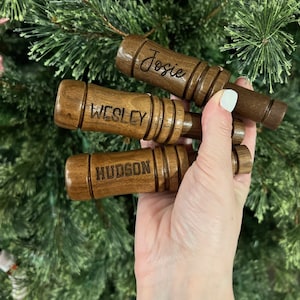 May include: Three wooden whistles with the names "Josie", "Wesley", and "Hudson" engraved on them. The whistles are brown and have a natural wood finish.