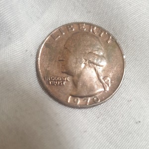 Może przedstawiać: Srebrna amerykańska moneta o wartości ćwierć dolara z datą 1970 i napisem "Liberty" oraz "In God We Trust".