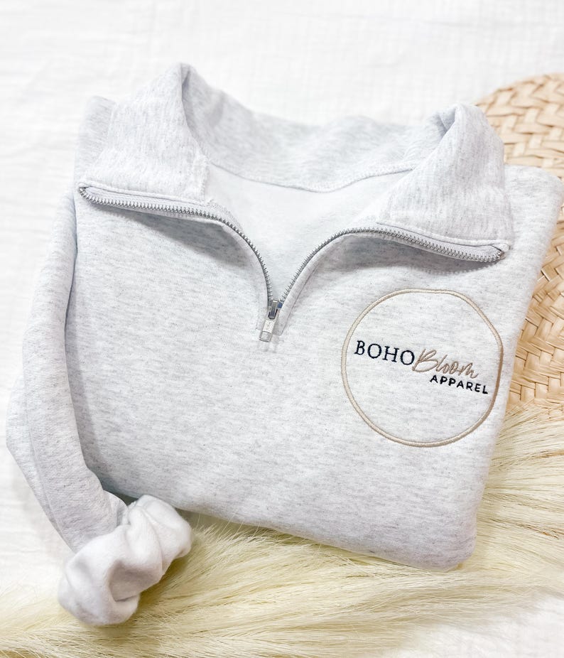 May include: A gray half-zip sweatshirt with a circular logo that says "BOHO Bloom APPAREL" in black text.