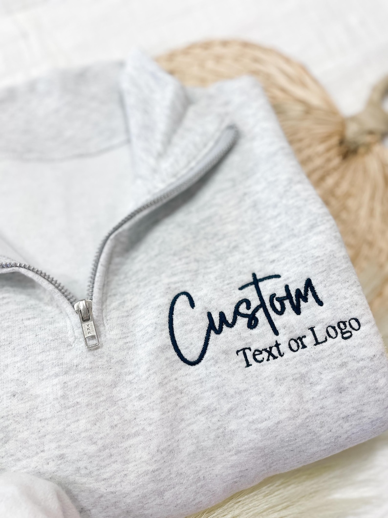 May include: A gray zippered sweatshirt with the text "Custom Text or Logo" in black.