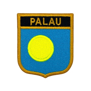 May include: Embroidered patch featuring the word "PALAU" in gold lettering on a black banner. The patch has a blue background with a yellow circle, and a gold border. The patch is shield-shaped.