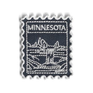 May include: A navy blue embroidered patch in the shape of a postage stamp. The patch features the word "MINNESOTA" at the top and a white embroidered landscape scene of mountains and water. The edges are scalloped with white thread.