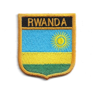 May include: Embroidered patch featuring the flag of Rwanda. The patch is shield-shaped with a gold border and the word "RWANDA" at the top. The flag design includes blue, yellow, and green horizontal stripes, with a yellow sun in the blue section.