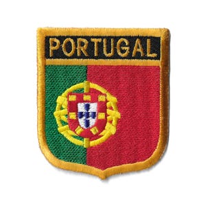Puede incluir: Un parche bordado en oro con la palabra "PORTUGAL" en letras negras y la bandera portuguesa en el centro. La bandera es verde y roja con un escudo de armas dorado.