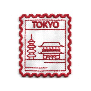 Puede incluir: Parche bordado con un diseño rojo y blanco de una pagoda y un templo japoneses, con la palabra "TOKYO" en la parte superior. El parche tiene un borde rojo festoneado, que se asemeja a un sello postal. Ideal para entusiastas de los viajes y coleccionistas de recuerdos.