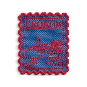 Può includere: Una toppa ricamata rettangolare a forma di francobollo con un bordo rosso smerlato. La toppa presenta uno sfondo in tessuto blu con ricami in filo rosso che raffigurano un paesaggio urbano e la parola CROATIA scritta in rosso in alto.
