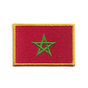 Puede incluir: Parche rectangular con la bandera de Marruecos. El parche tiene un fondo rojo con una estrella verde de cinco puntas en el centro. El borde es amarillo.