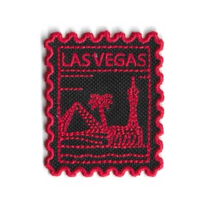 Puede incluir: Parche bordado con un diseño de Las Vegas. El parche tiene un fondo negro con costuras rojas que delinean el texto "LAS VEGAS" y monumentos icónicos. El parche tiene un borde rojo festoneado.