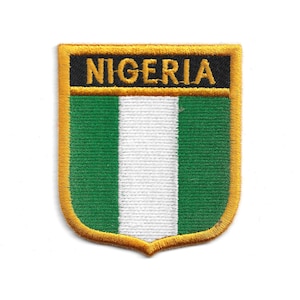 May include: Embroidered patch featuring the word "NIGERIA" in gold lettering on a black background. The patch has a green and white striped design, with a gold border. The patch is in the shape of a shield.