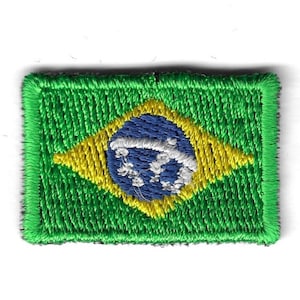 Pode incluir: Patch bordado com a bandeira do Brasil. O design inclui uma borda verde, um losango amarelo, um círculo azul com estrelas brancas e um fundo verde. O patch tem formato retangular.