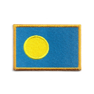 May include: A rectangular patch featuring the flag of Palau. The flag has a light blue background with a yellow circle in the center-left. The patch is bordered with a gold-colored trim.