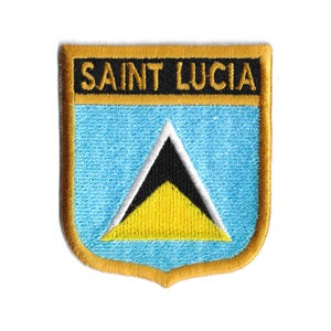 Pode incluir: Um remendo bordado com a bandeira de Santa Lúcia. O remendo tem a forma de um escudo com uma borda dourada e as palavras "SAINT LUCIA" em letras pretas no topo. A bandeira é azul com um triângulo amarelo com um triângulo preto dentro.