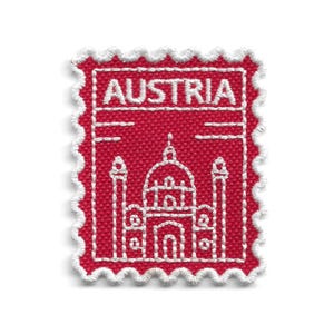 May include: A rectangular embroidered patch with a red background and white scalloped edges. The design features white stitching of a building with a central dome and two towers, with the word AUSTRIA stitched in white letters at the top.