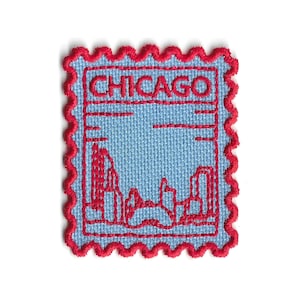 Può includere: Toppa ricamata a forma di francobollo con il nome della città "CHICAGO" in lettere rosse. La toppa ha uno sfondo azzurro chiaro con un disegno dello skyline rosso e un bordo smerlato rosso.