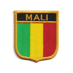 May include: Embroidered patch with the word "MALI" above a vertical tricolour design of green, yellow, and red. The patch has a gold border and a shield shape, suitable for application on clothing or accessories.