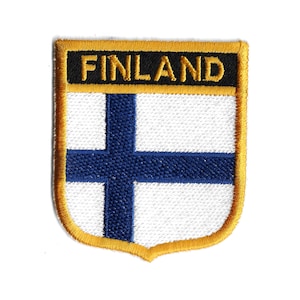 May include: An embroidered patch featuring the Finnish flag, with a blue cross on a white background. The patch is surrounded by a gold border and has the word "FINLAND" in yellow letters on a black background.