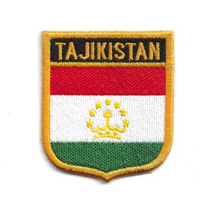 May include: Embroidered patch depicting the flag of Tajikistan. The patch is shield-shaped with a gold border. The flag design features horizontal stripes of red, white, and green, with a gold emblem in the centre. The word "TAJIKISTAN" is embroidered in gold.
