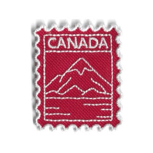 May include: A red fabric patch featuring a white stitched mountain range design and the word "CANADA". The patch is shaped like a postage stamp with a white scalloped border. The design is simple and clean.