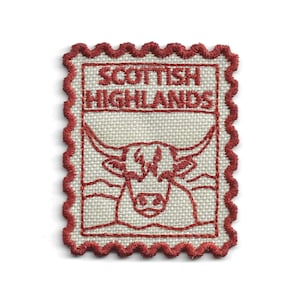 May include: A rectangular embroidered patch with a scalloped red border on a light beige fabric base. The design features the red stitched text "SCOTTISH HIGHLANDS" above a stylized outline of a Highland cow with long horns in red thread.