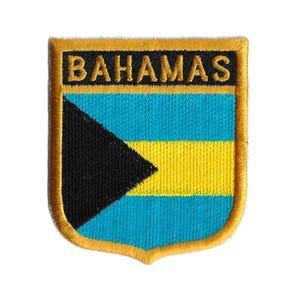 Puede incluir: Un parche bordado en oro con la bandera de las Bahamas. La bandera presenta un triángulo negro, una franja amarilla y un fondo azul turquesa. Las palabras "BAHAMAS" están bordadas en negro sobre una pancarta dorada sobre la bandera.