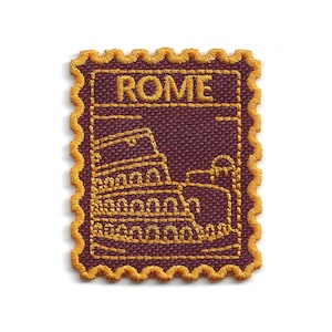 May include: A burgundy embroidered patch with gold stitching, depicting the Colosseum and the word "ROME". The patch has a decorative, scalloped edge, resembling a postage stamp. The design is a travel-themed souvenir.