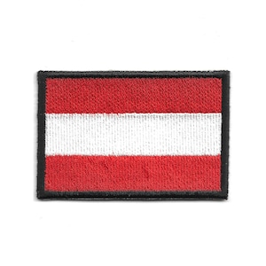 Pode incluir: Patch retangular bordado com a bandeira da Áustria. O design da bandeira tem três listras horizontais: vermelha na parte superior e inferior, com uma listra branca no centro. O patch é contornado com uma borda preta.