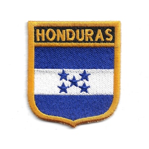 May include: Embroidered patch featuring the flag of Honduras. The design includes a blue and white striped background with five blue stars, and the word "HONDURAS" in gold lettering. The patch has a gold border.