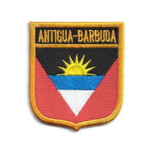 May include: Embroidered patch featuring the flag of Antigua and Barbuda. The patch has a shield shape with a gold border. The design includes a black top, a yellow sun, blue and white stripes, and a red bottom.