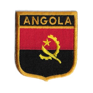 May include: A gold embroidered patch with the word "ANGOLA" in black lettering and the Angolan flag in the center. The flag features a red, black, and yellow color scheme with a yellow gear and star.